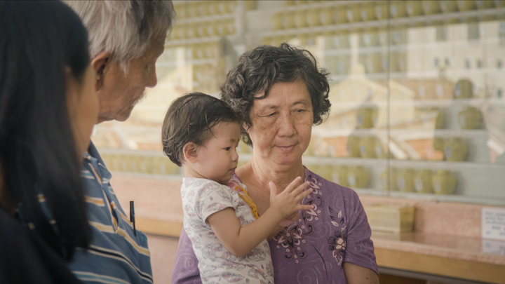 Madam Teoh with one of her grandchildren. The next generation of children in the Teoh family are brought along to offer prayers before Beng Hock’s shrine