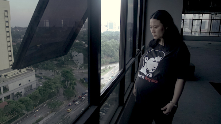 Teoh Lee Lan looking out the 14th floor window where her brother fell to his death, 10 years ago
